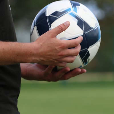 Ein Schiedsrichter hält einen Fußball in der Hand.