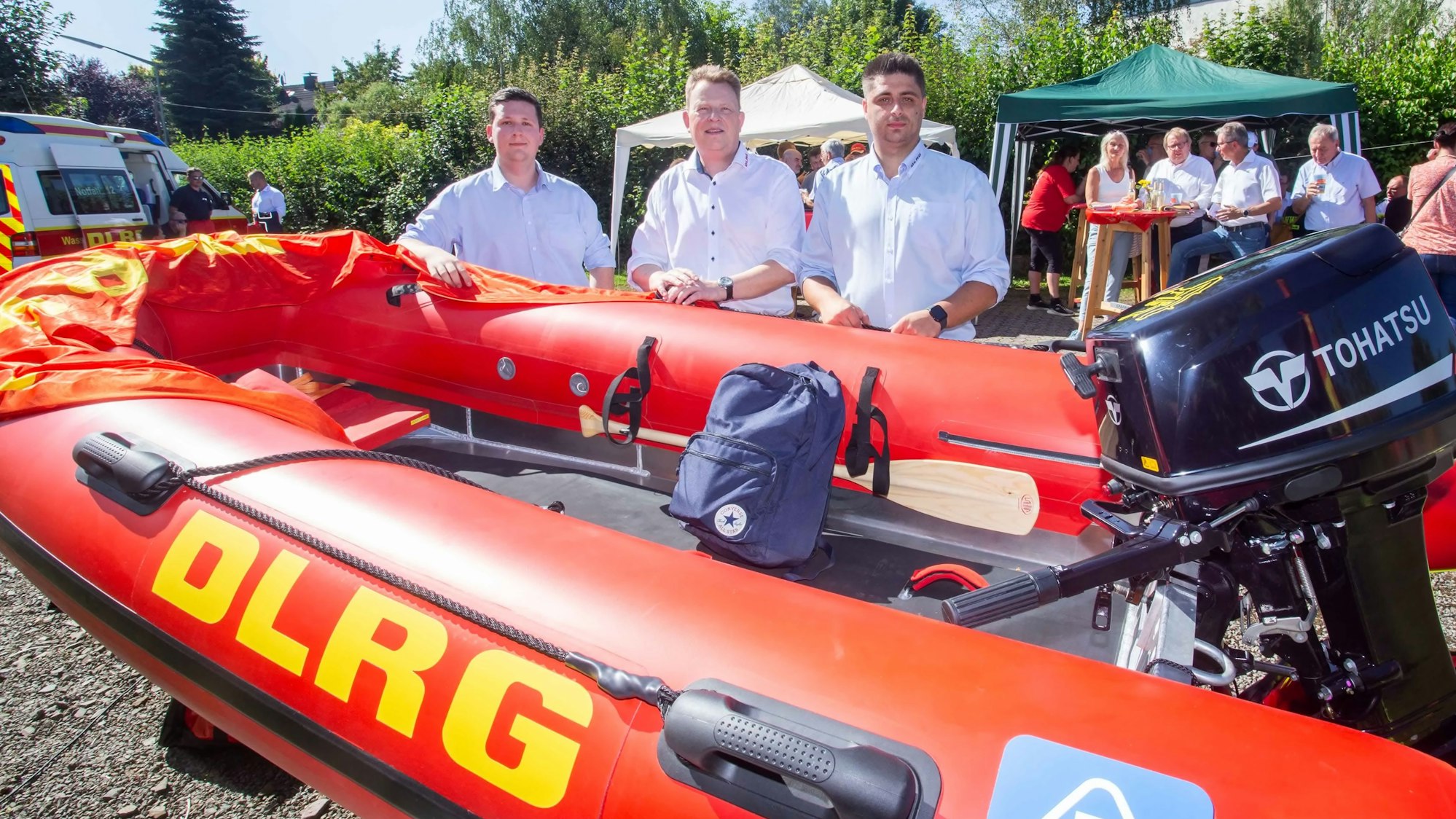 Drei Rettungsschwimmer präsentieren ein neues Rettungsboot.