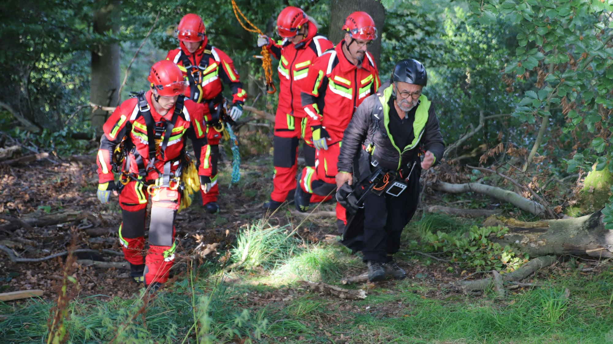 Vier Feuerwehrleute begleiten einen Gleitschirmflieger zum Rettungsdienst.