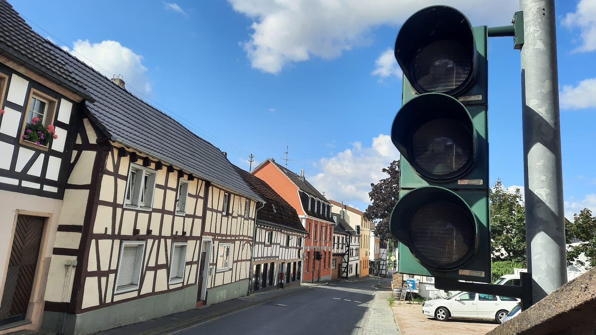 Eine ausgeschaltete Ampel, im Hintergrund eine Straße und Fachwerkhäuser.