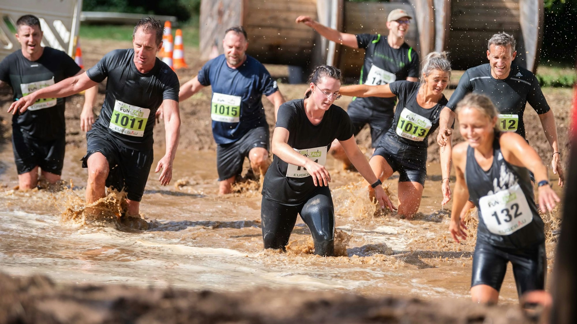 Das Bild zeigt einige Teilnehmer, die ein großes Wasserhindernis durchqueren.