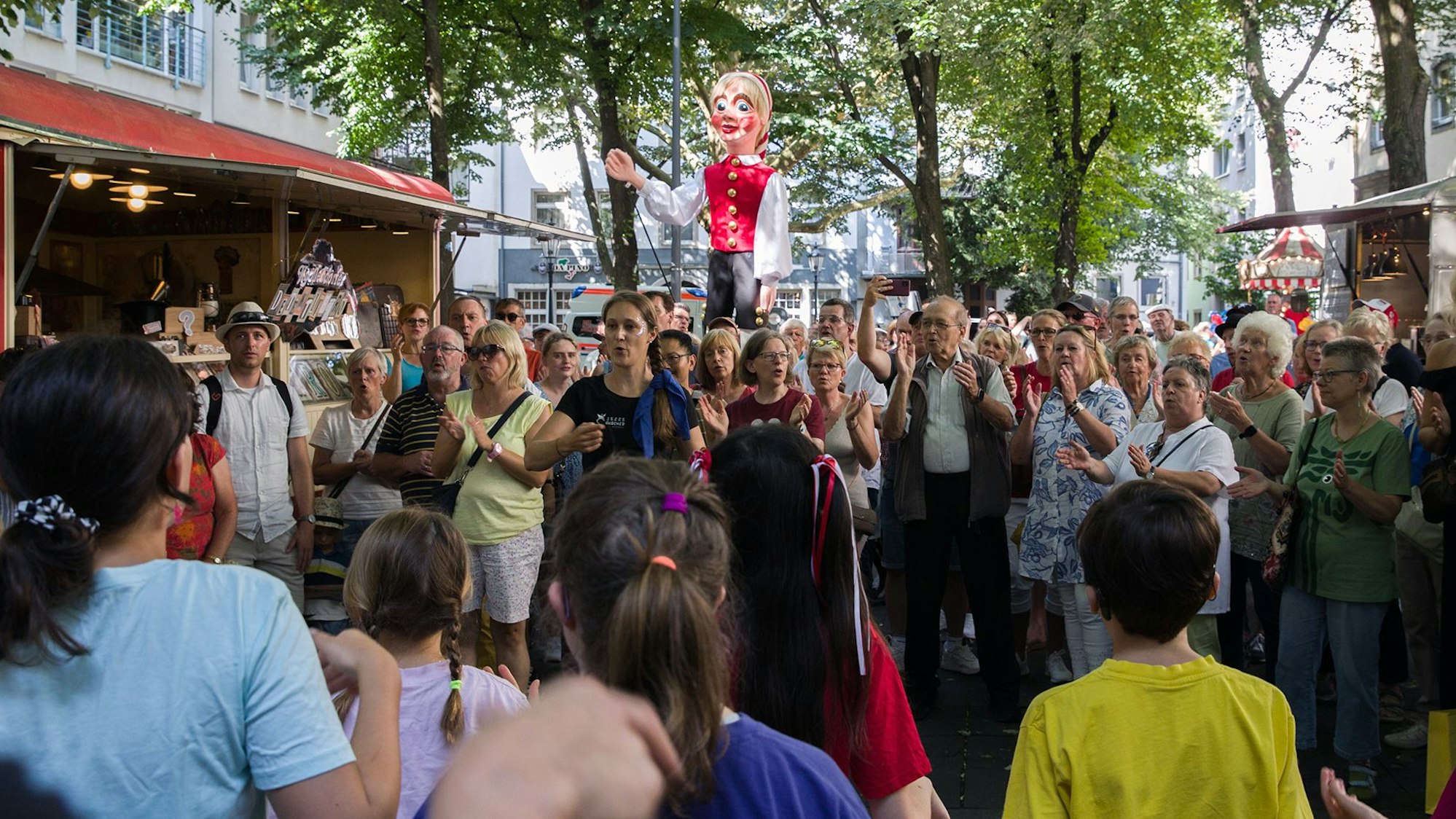 Gäste beim Familienfest des Hänneschen-Theaters auf dem Eisenmarkt singen Lieder.