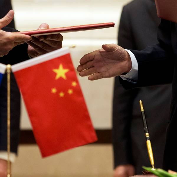 Ein Mitglied der Europäischen Kommission (l) bereitet sich auf den Austausch von Dokumenten mit der chinesischen Delegation vor.
