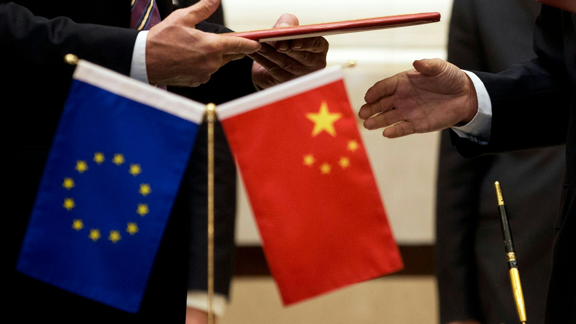 Ein Mitglied der Europäischen Kommission (l) bereitet sich auf den Austausch von Dokumenten mit der chinesischen Delegation vor.