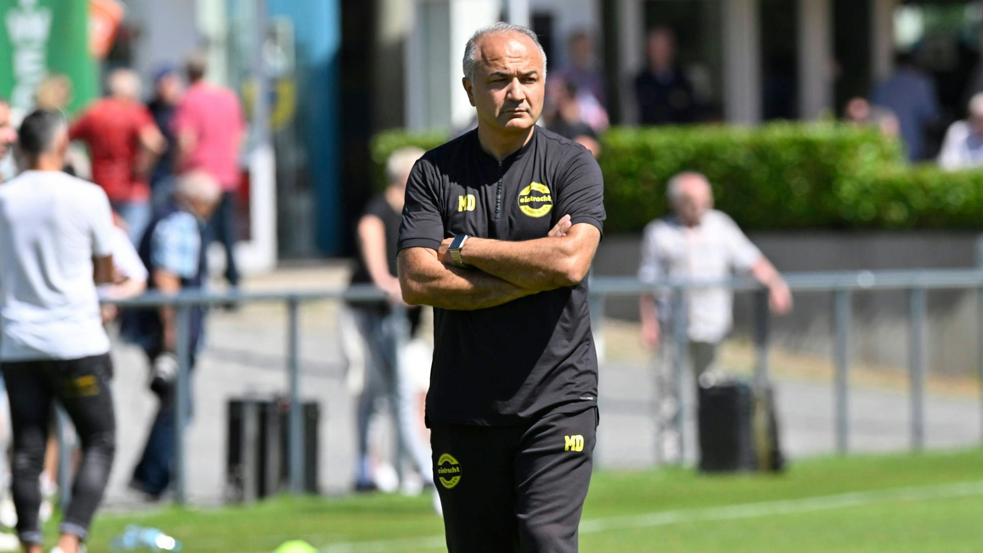 Bild eines Fußballtrainers, der allein über den Rasen geht.