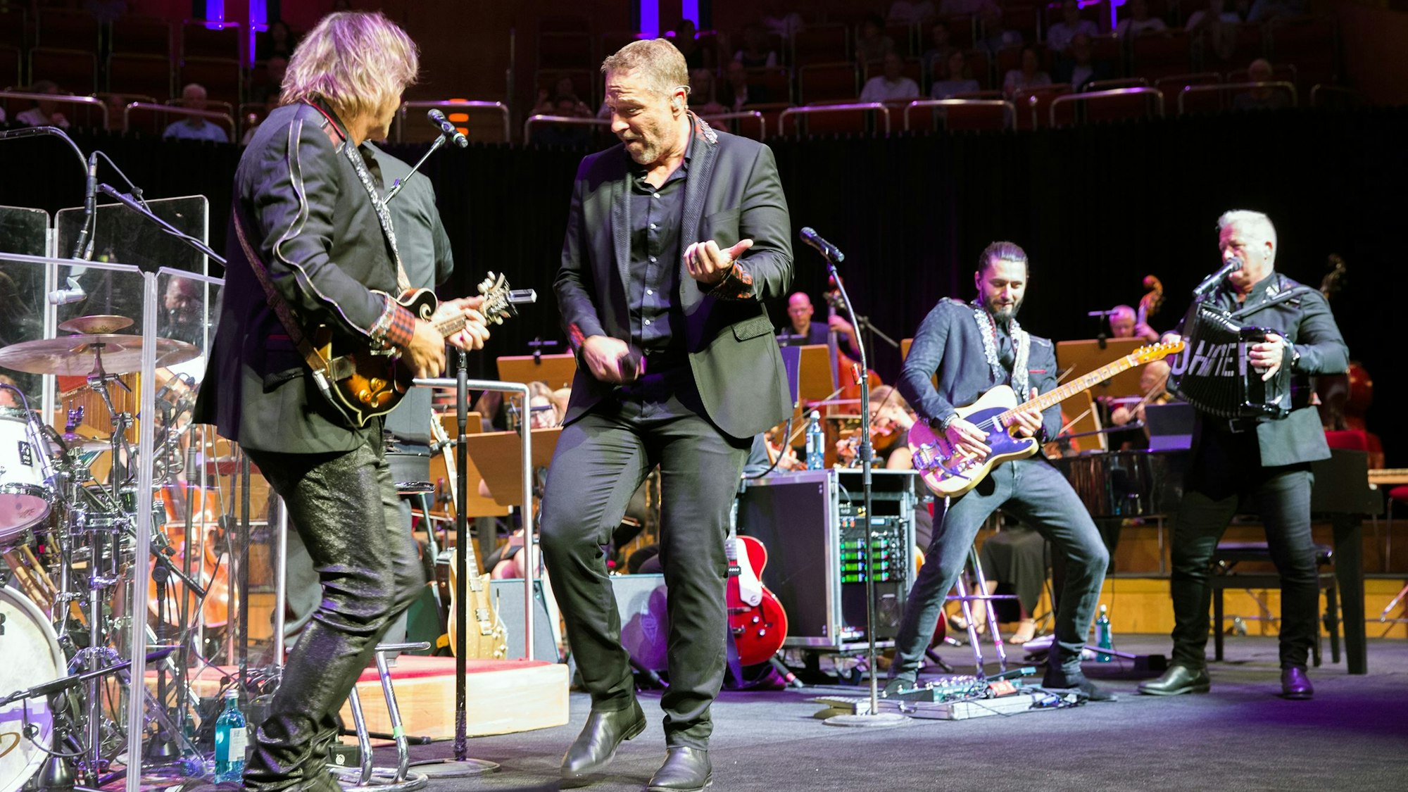 Zu sehen sind drei Mitglieder der Karnevalsband Höhner auf der Bühne der Kölner Philharmonie.