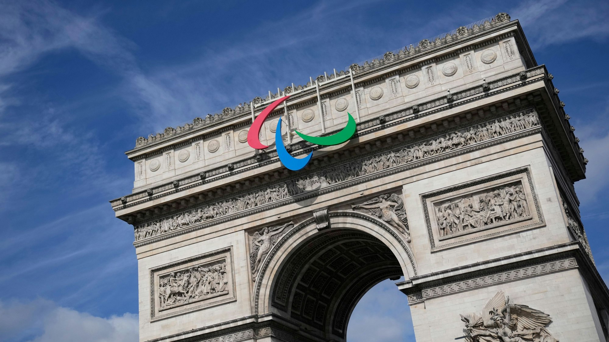 ARCHIV - 28.06.2024, Frankreich, Paris: Das Symbol der Paralympischen Spiele hängt am Arc de Triomphe. Die Paralympischen Spiele in Paris 2024 finden vom 28. August bis 8. September statt.
Die Paralympics finden in Frankreich statt. Denn dort wurden in diesem Jahr auch die Olympischen Spiele ausgetragen. (zu dpa: «Was sind die Paralympischen Spiele?») Foto: Christophe Ena/AP/dpa - Honorarfrei nur für Bezieher des Dienstes dpa-Nachrichten für Kinder +++ dpa-Nachrichten für Kinder +++