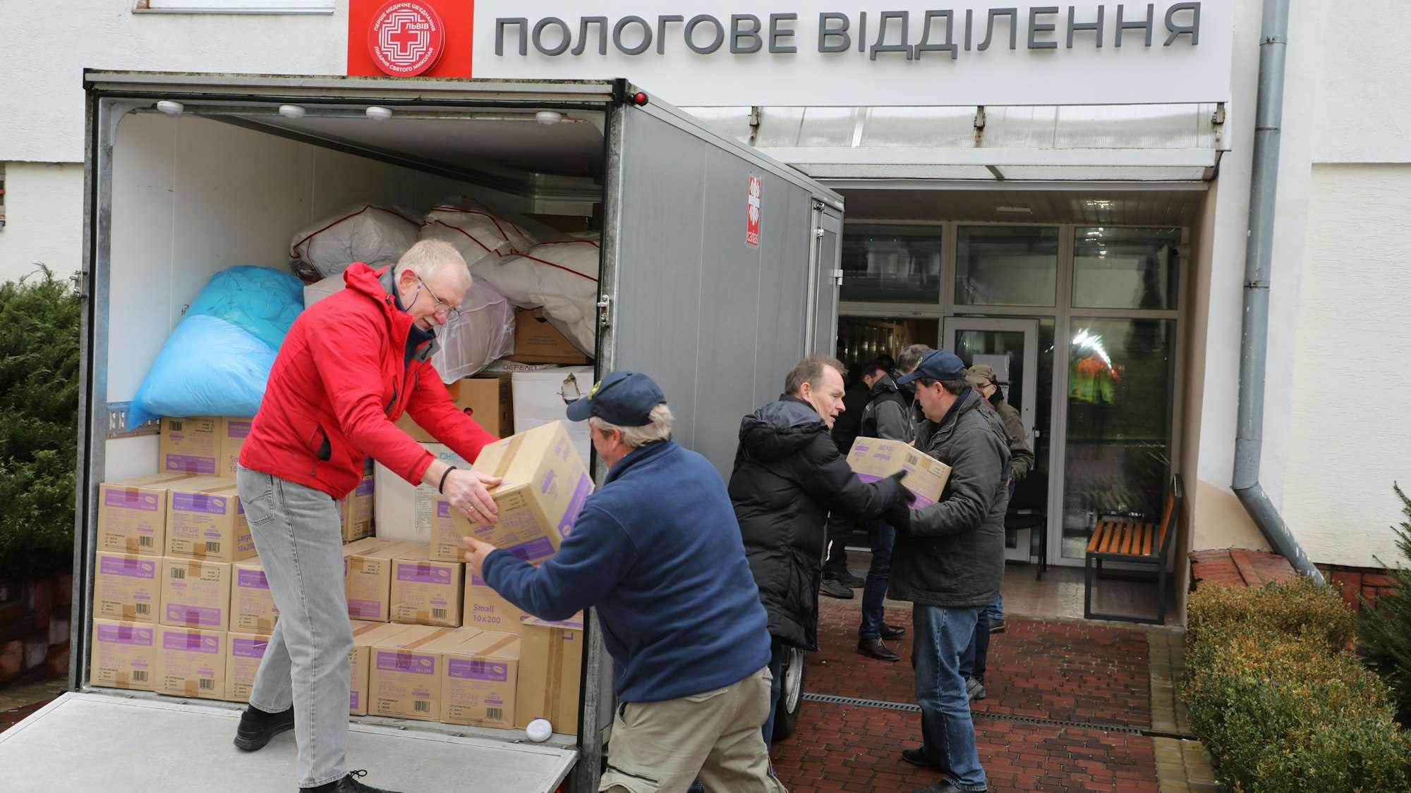 Helfer der Humanitären Hilfe Bergisch Gladbach und der Humanitären Hilfe Overath laden Medikamenten am Kinderkrankenhaus der westukrainischen Stadt Lviv aus einem Transporter.