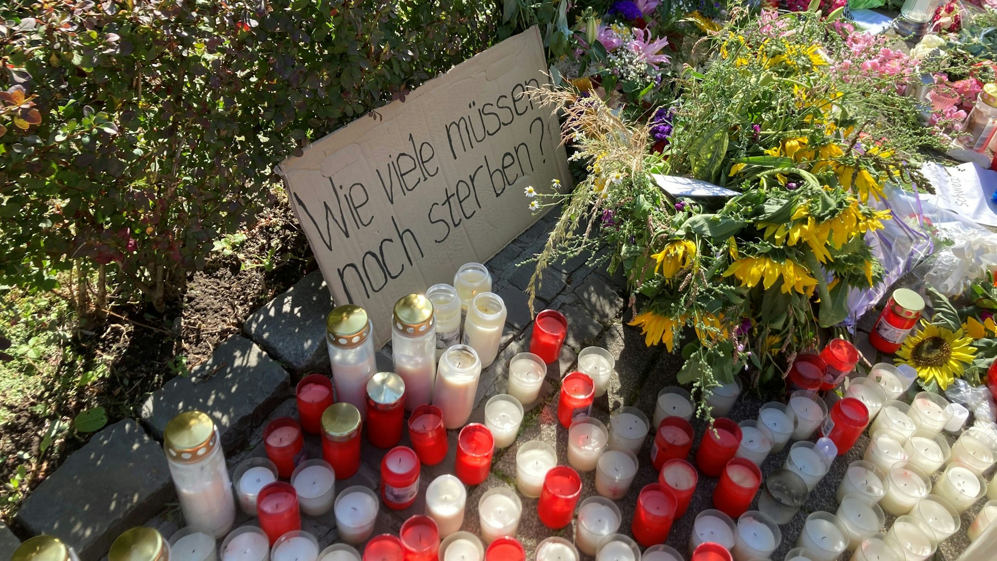 Auf einer Papptafel steht zu lesen: „Wie viele noch?“