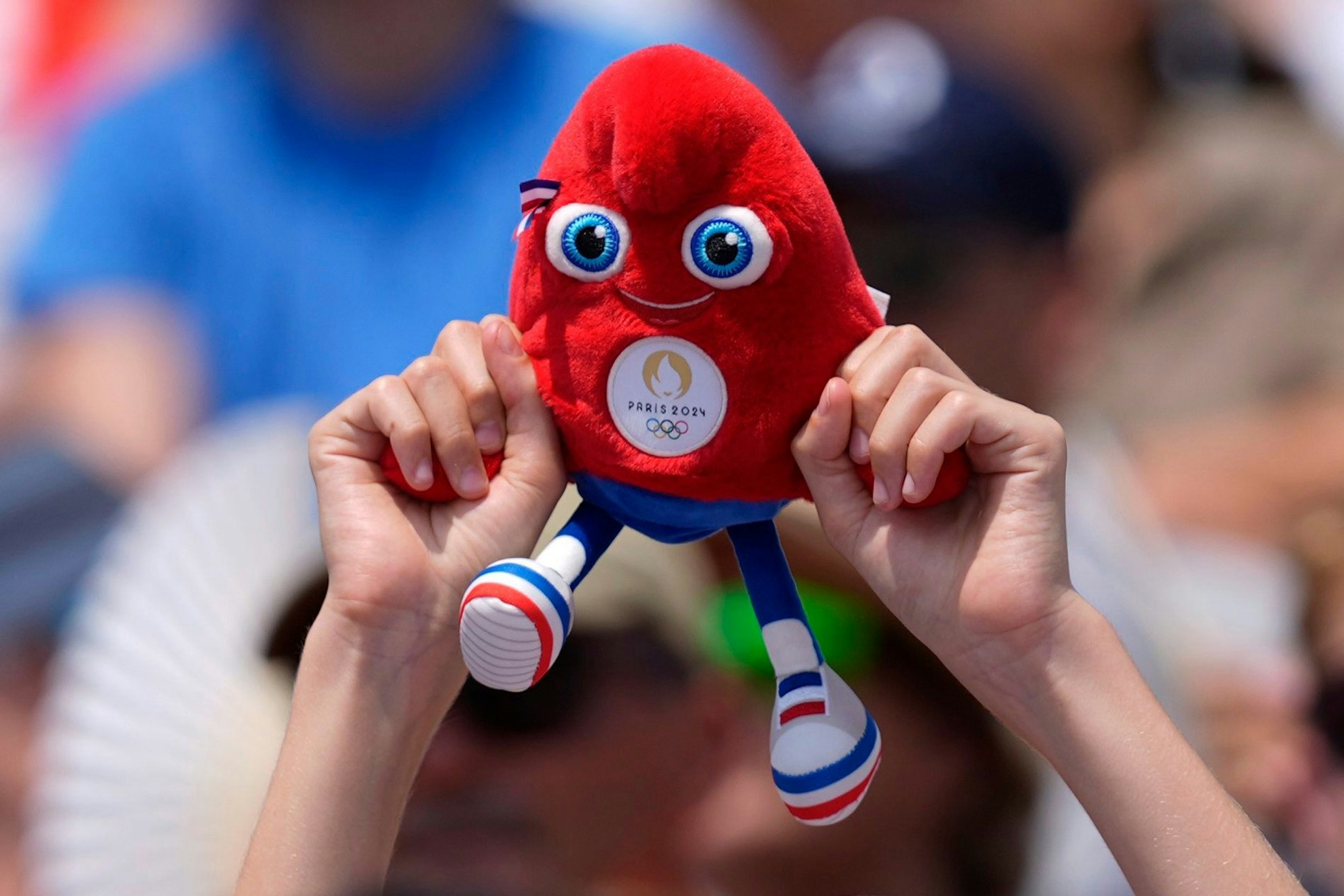 A spectator holds a Phryge, the Olympic mascot, while watching a beach volleyball match at the 2024 Summer Olympics, Friday, Aug. 2, 2024, in Paris, France. (AP Photo/Robert F. Bukaty)