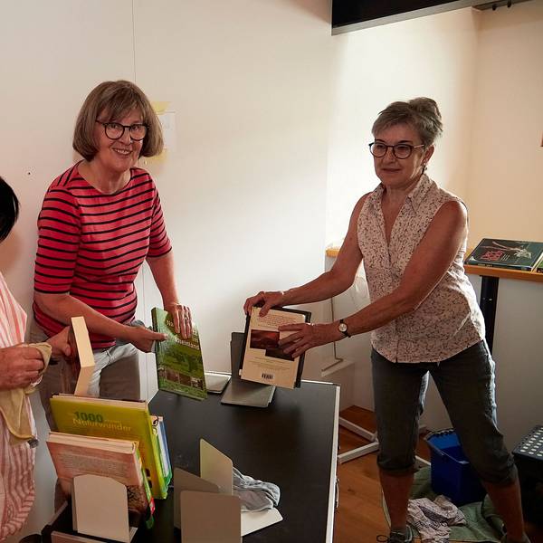 Die drei Frauen stauben Bücher ab.