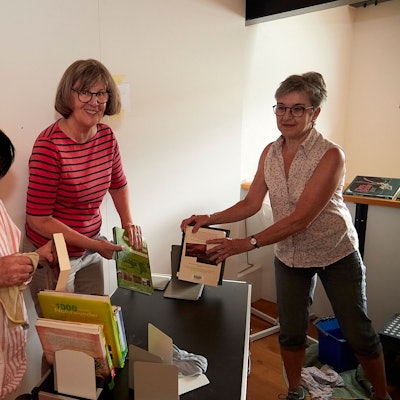 Die drei Frauen stauben Bücher ab.