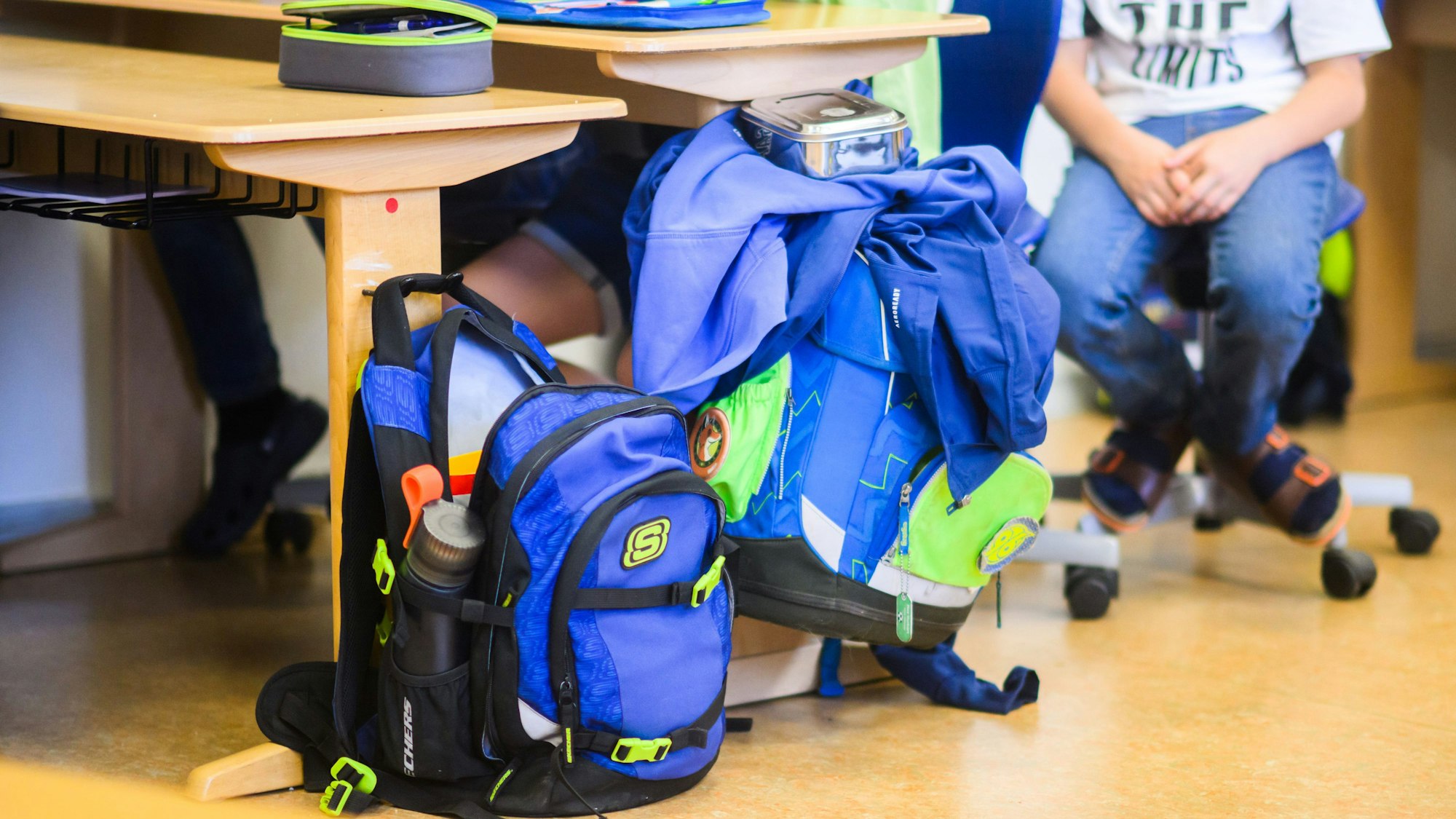 Schüler sitzen neben ihren Schulranzen im Klassenraum.