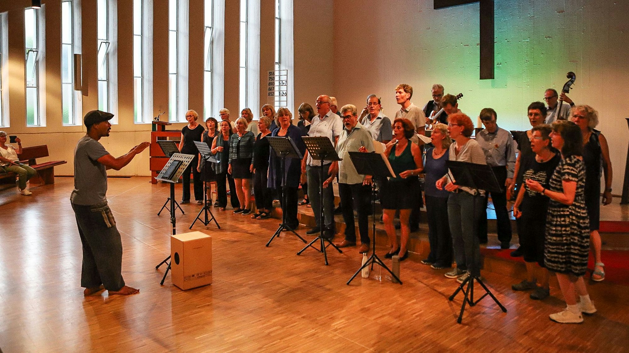 Ein Chorleiter steht vor einem Chor in einer Kirche und leitet ihn an.