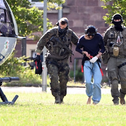 Der Täter des Messerangriffs von Solingen wird zu einem Hubschrauber gebracht. Zuvor war der Verdächtige dem Ermittlungsrichter beim Bundesgerichtshof (BGH) vorgeführt worden, der Haftbefehl erlassen hat.