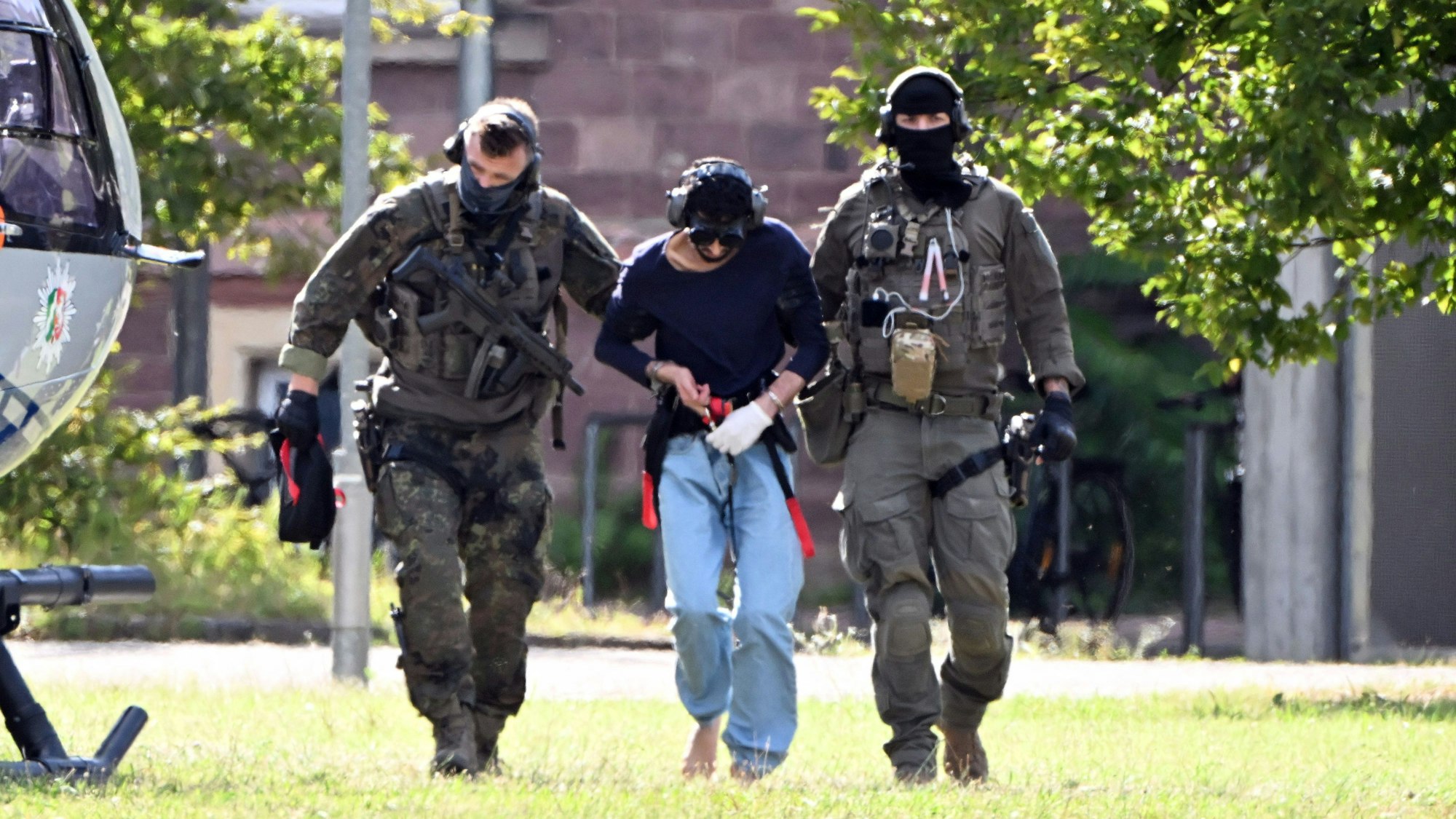 Der Täter des Messerangriffs von Solingen wird zu einem Hubschrauber gebracht. Zuvor war der Verdächtige dem Ermittlungsrichter beim Bundesgerichtshof (BGH) vorgeführt worden, der Haftbefehl erlassen hat.