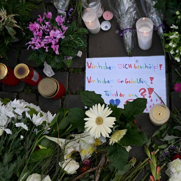 Auf einem Schild inmitten von Blumen und Kerzen ist zu lesen: „Wir haben dich beschützt. Wir haben dir geholfen. Tötest du uns?“