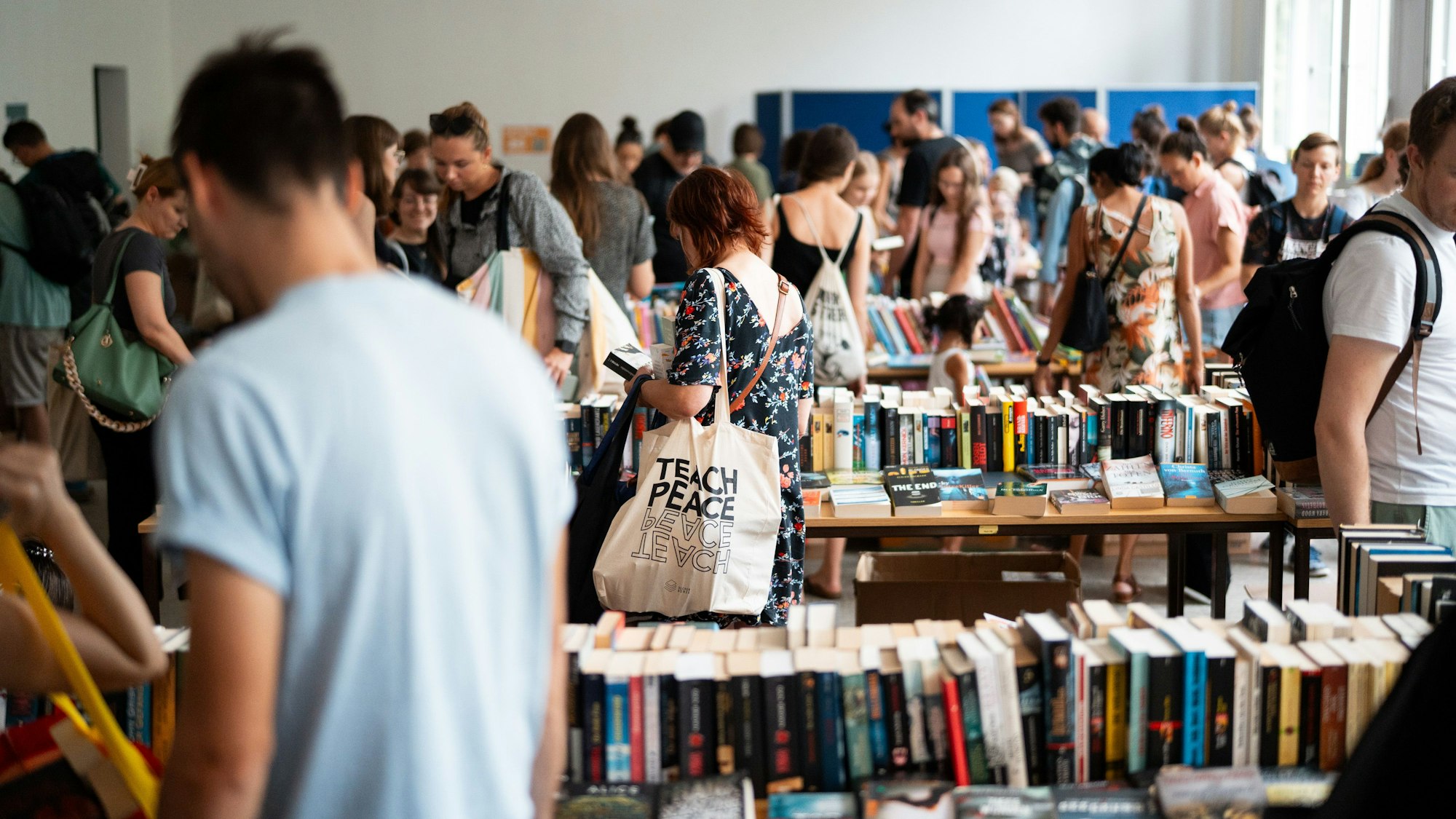 Zu sehen sind viele Menschen, die Tische voller Bücher durchstöbern.