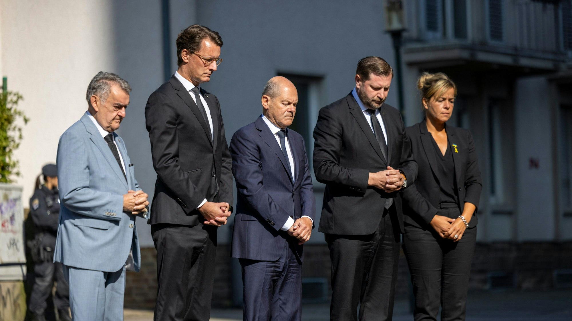 26.08.2024, Nordrhein-Westfalen, Solingen: Herbert Reul (CDU, l-r), Innenminister von Nordrhein-Westfalen, Hendrik Wüst (CDU), Ministerpräsident von Nordrhein-Westfalen, Bundeskanzler Olaf Scholz (SPD), Tim Kurzbach (SPD), Bürgermeister von Solingen, und Mona Neubaur (Grüne), stellvertretende Ministerpräsidentin von Nordrhein-Westfalen, stehen mit gefalteten Händen vor Blumen, die in Gedenken an die Opfer niedergelegt wurden. Bei einer Messerattacke auf der 650-Jahr-Feier der Stadt Solingen am 23. August hatte es drei Todesopfer und Verletzte gegeben. Foto: Thomas Banneyer/dpa +++ dpa-Bildfunk +++