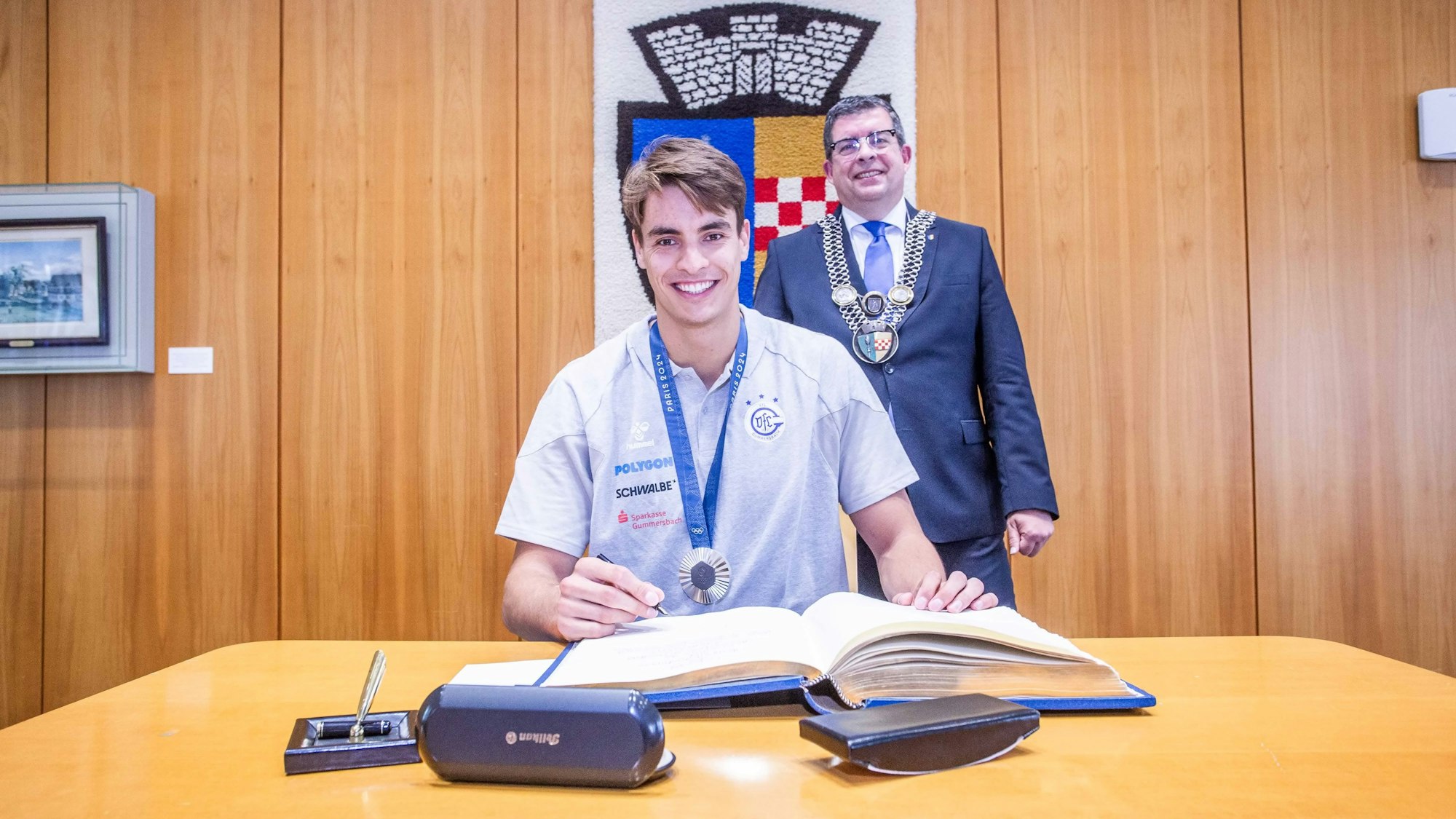 In Anwesenheit von Gummersbachs Bürgermeister Frank Helmenstein trägt sich Handballer Julian Köster ins Goldene Buch der Stadt ein.
