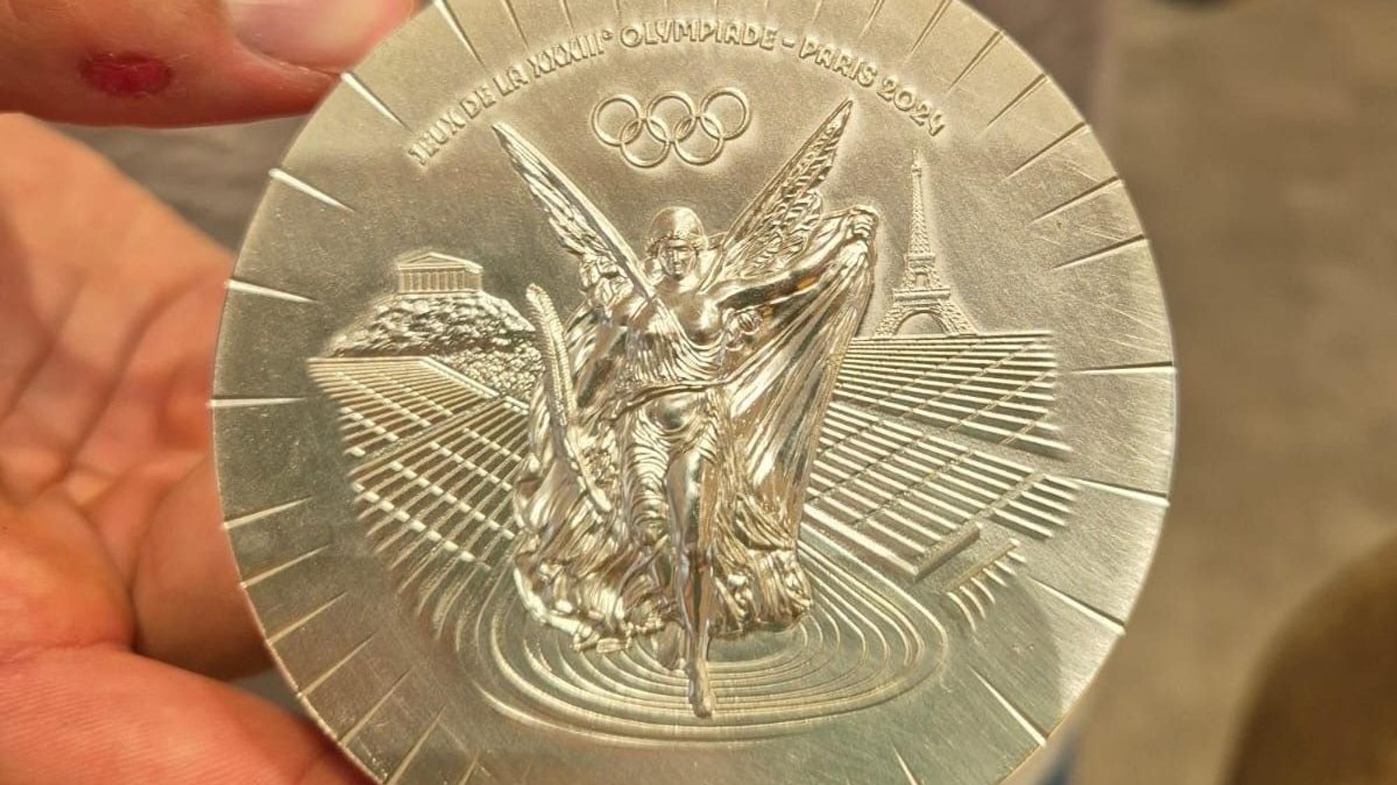 Handballer Julian Köster hält seine olympische Silbermedaille aus Paris in den Händen.