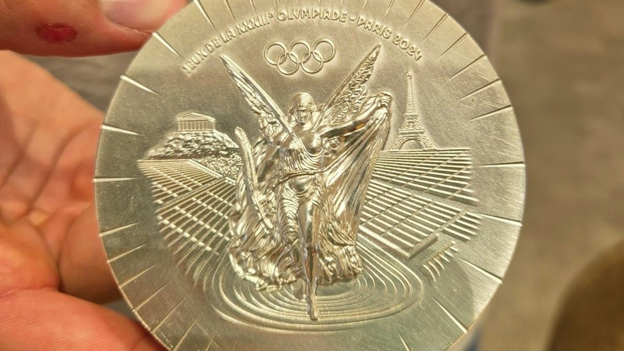 Handballer Julian Köster hält seine olympische Silbermedaille aus Paris in den Händen.