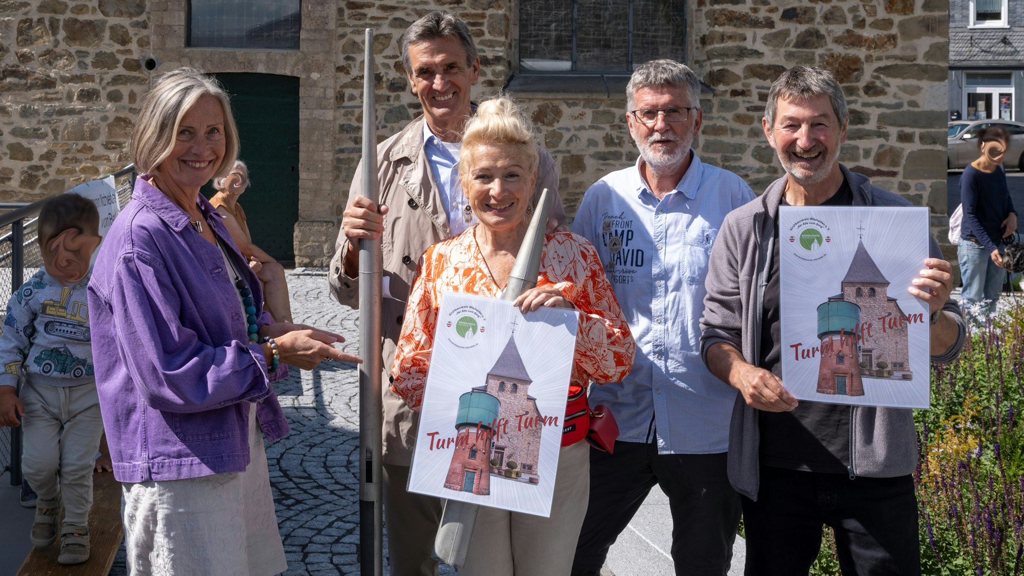 Männer und Frauen stehen mit Orgelpfeifen in der Hand vor einer Kirche.