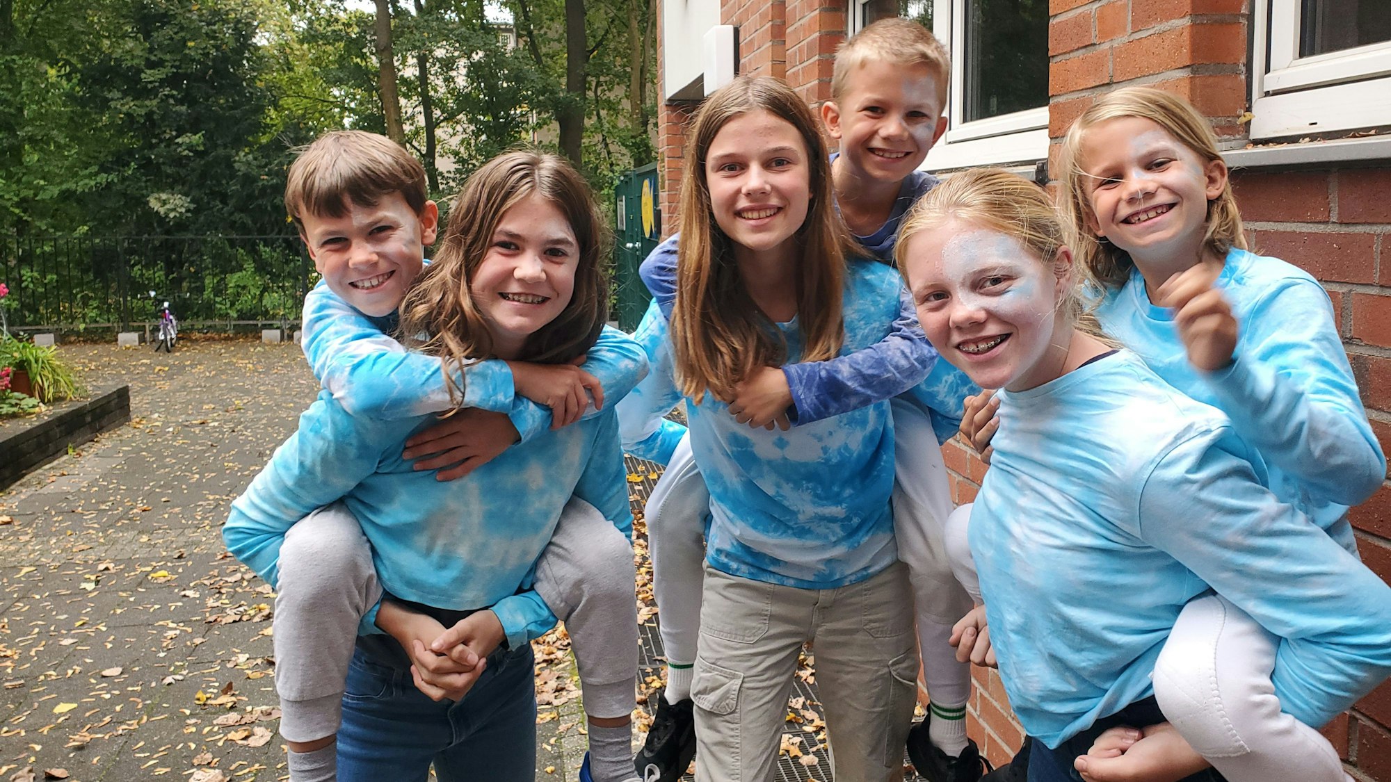 Eine Gruppe Kindern mit hellblauen Pullis mit Batikmuster.
