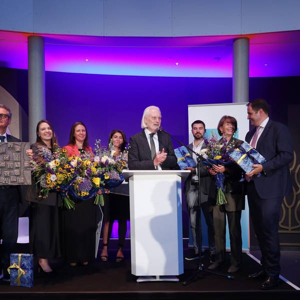 Vertreter des Vereins Blau-Gelbes Kreuz nehmen auf einer Bühne den Altstadtpreis entgegen