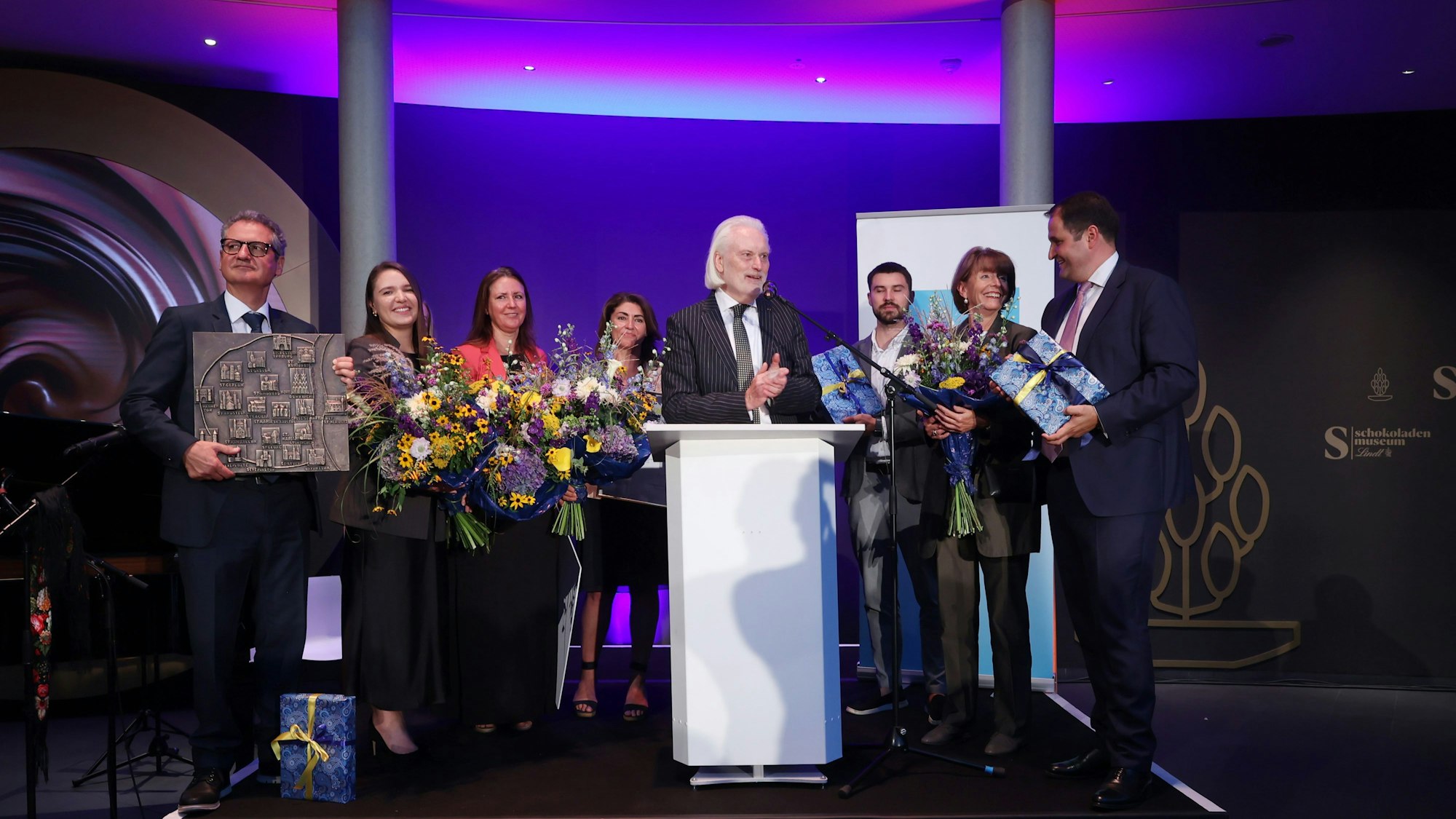Vertreter des Vereins Blau-Gelbes Kreuz nehmen auf einer Bühne den Altstadtpreis entgegen