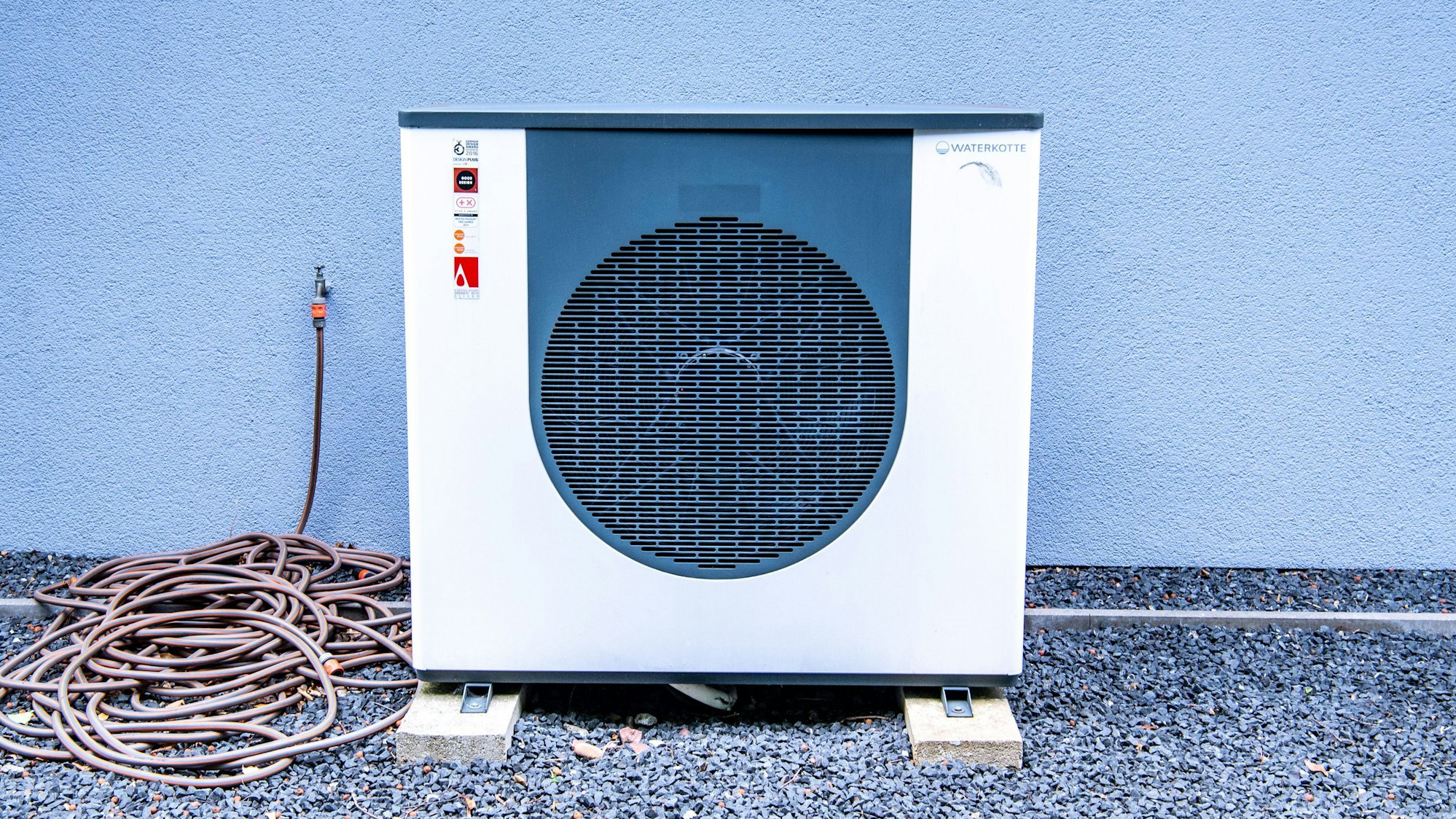 Die Lüftungsanlage einer Wärmepumpe vor einem Haus.