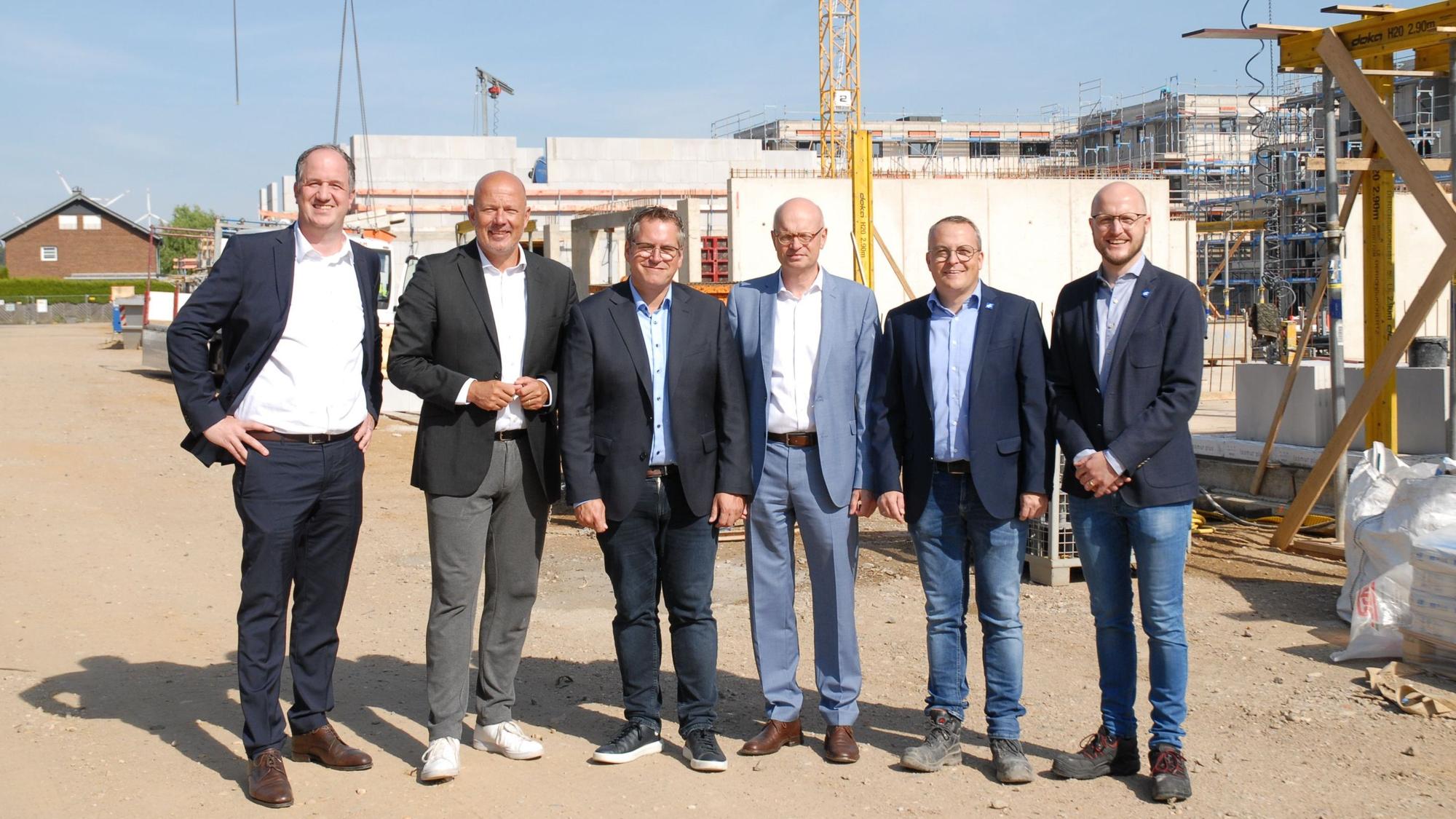 Männer stehen vor einer Baustelle.