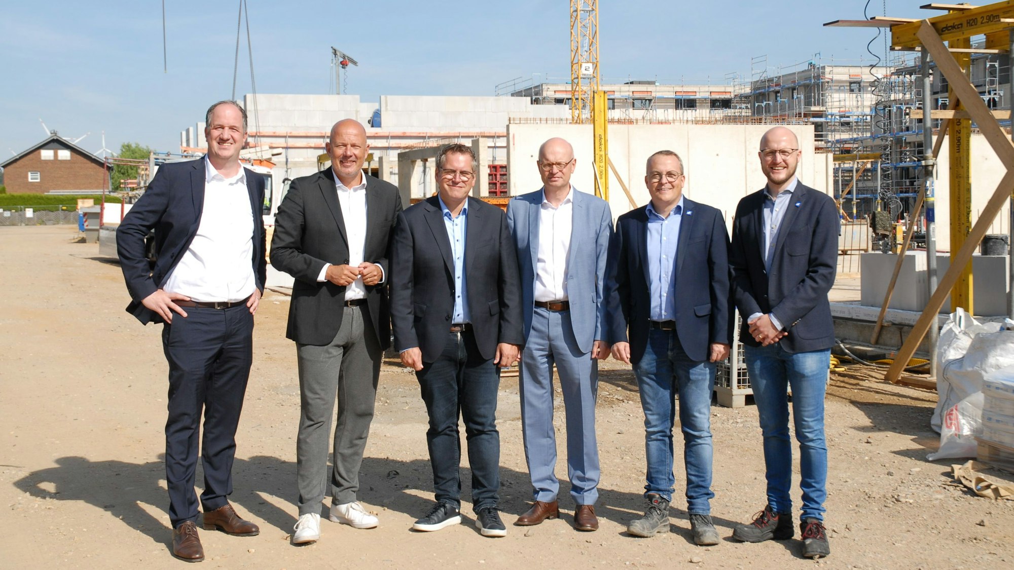 Männer stehen vor einer Baustelle.