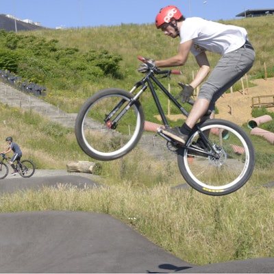 Ein Fahrradfahrer fliegt über eine Asphaltpiste.