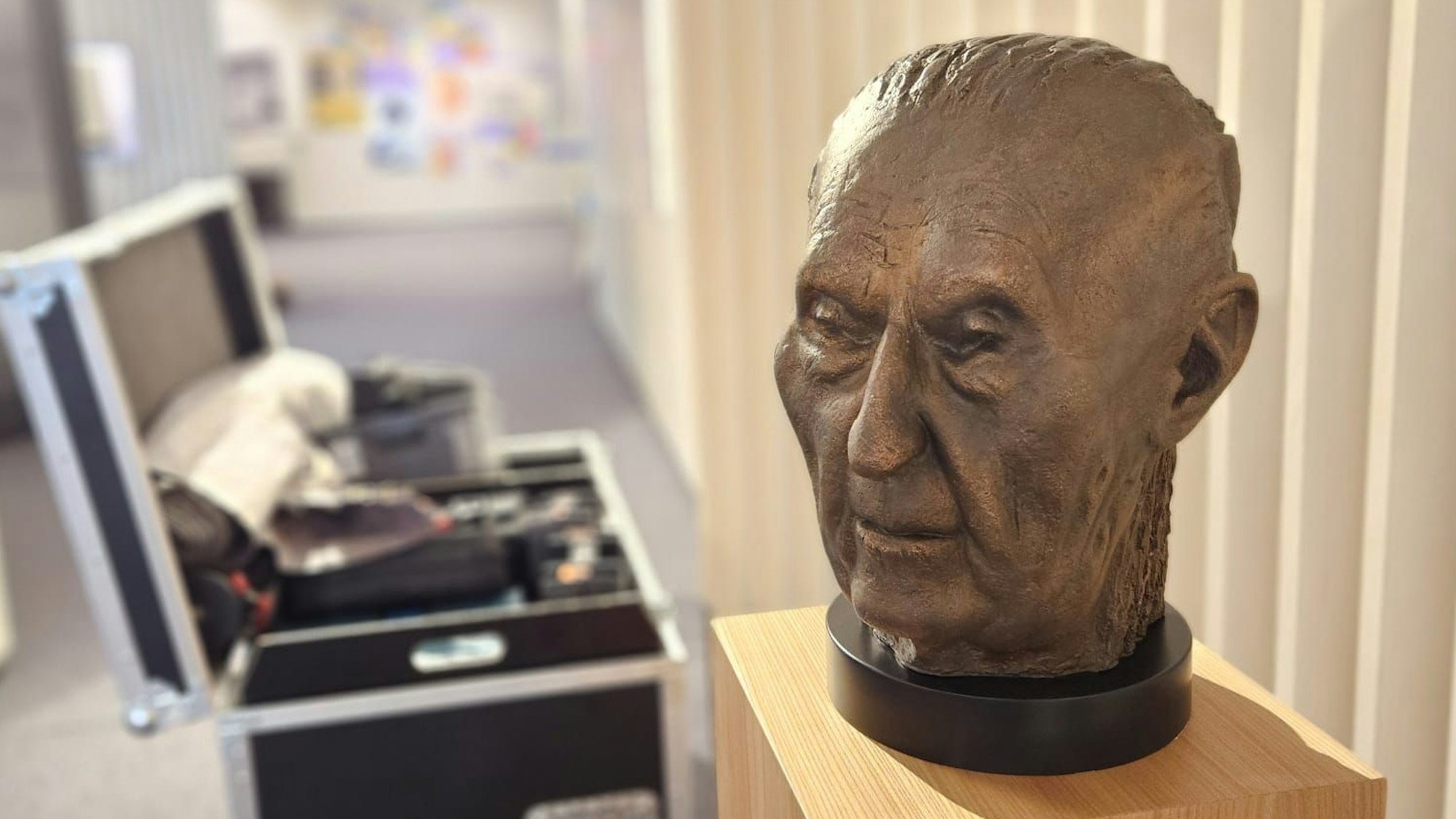 Eine Büste von Konrad-Adenauer auf einem Podest, daneben ein offener Werkzeugkoffer.