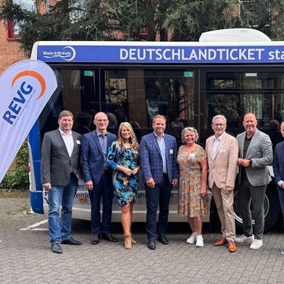 Das Foto zeigt eine Gruppe von Männern und Frauen vor einem Bus mit der Aufschrift „Deutschlandticket statt Führerschein“: