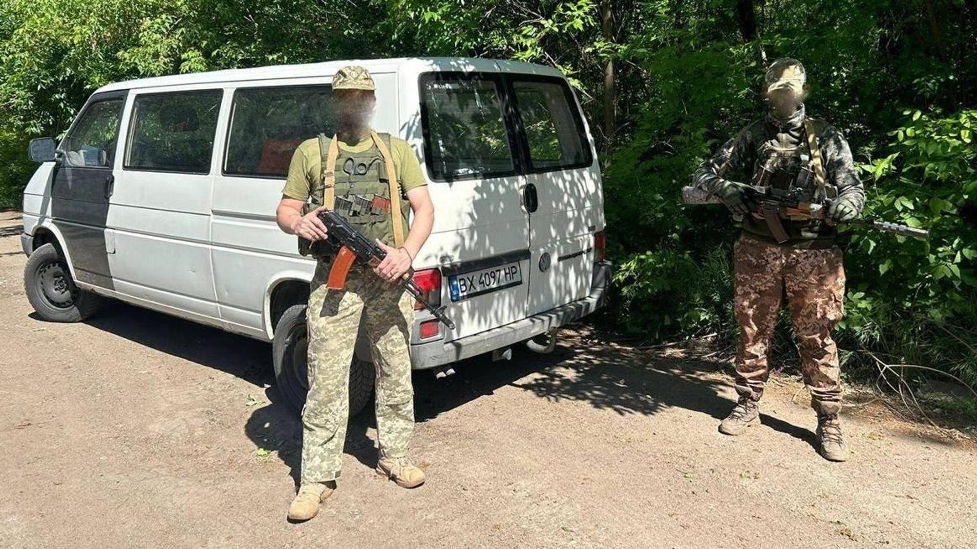 Zwei bewaffnete Ukrainer stehen vor einem VW-Bus.