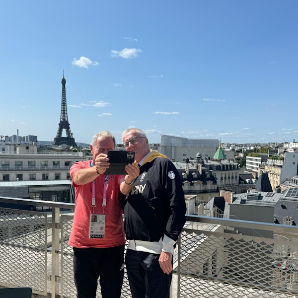 Zwei Männer machen im Rahmen der Paralympics in Paris ein Selfie mit dem Eiffelturm im Hintergrund.