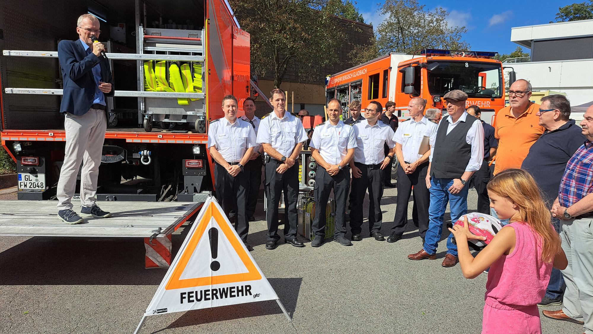 Bürgermeister Frank Stein steht auf der Ladebordwand eines Feuerwehrfahrzeugs und spricht zu den Gästen des Festes zum 125-Jährigen des Löschzugs Refrath.