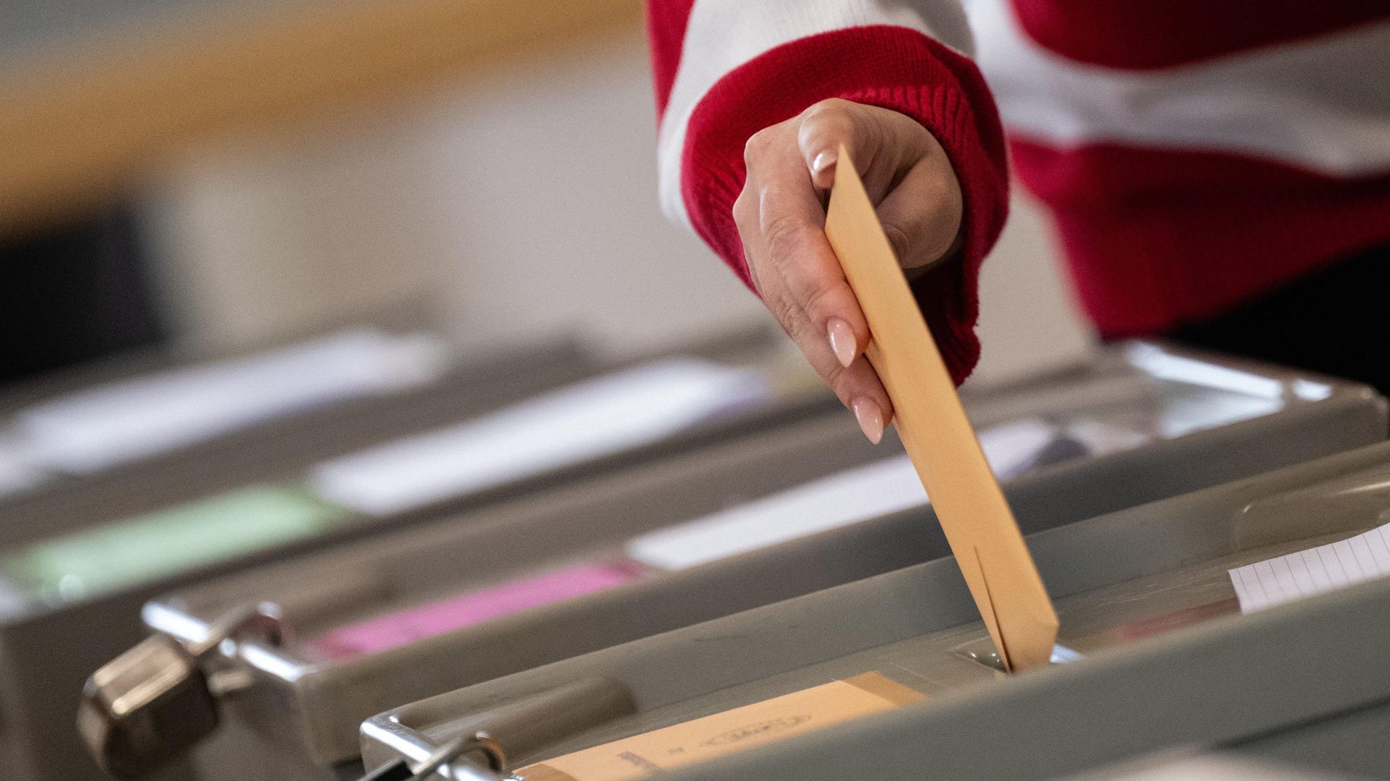 Eine Wählerin wirft in einem Wahlraum im Rathaus im Sigmaringer Stadtteil Laiz einen Wahlschein in eine Urne.