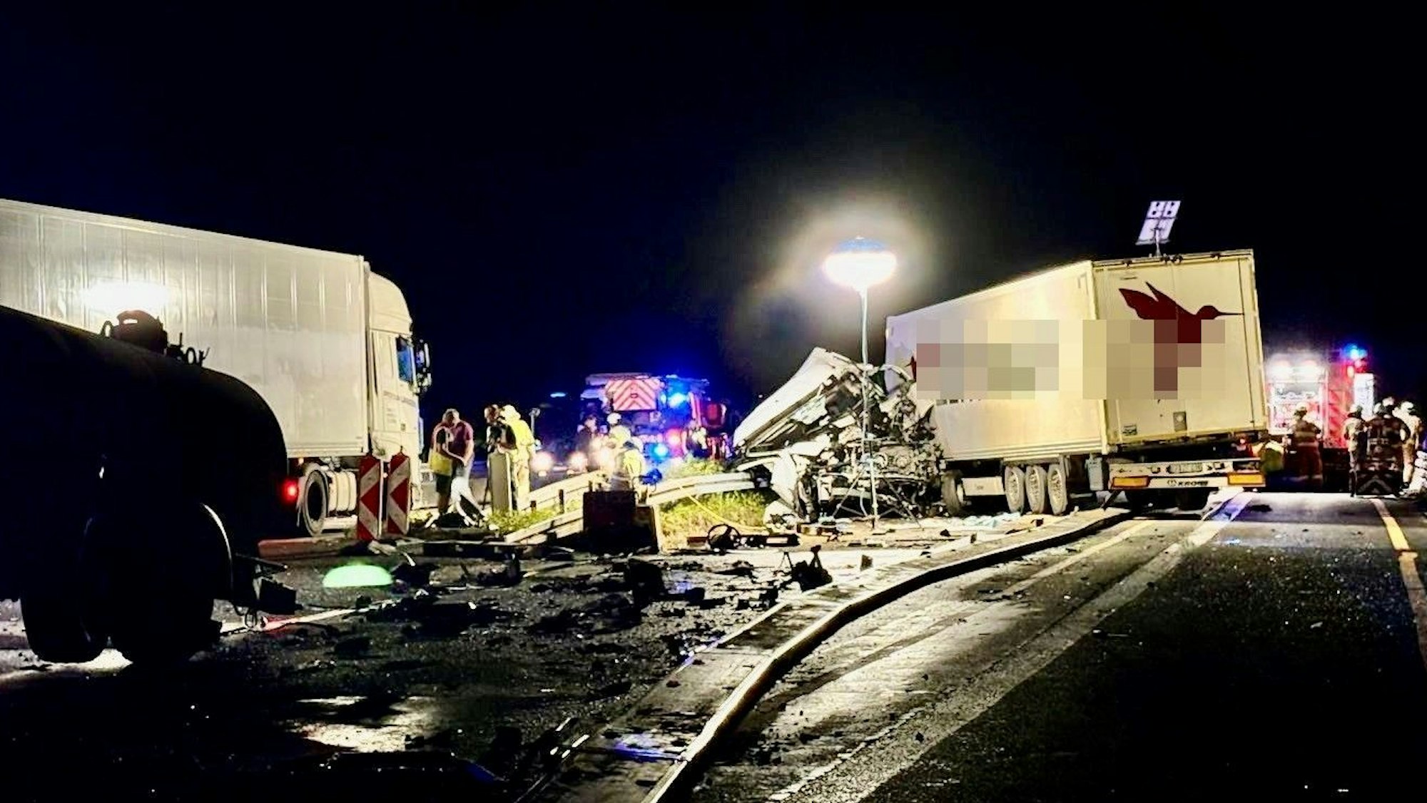 Ein schwer beschädigter Lkw steht in der Nacht (27.8.) auf der A4 bei Bensberg. Feuerwehr und Polizei sind im Einsatz, die Unfallstelle ist ausgeleuchtet.