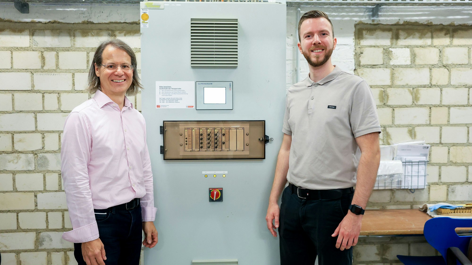 Mathias Diebold und Marius Ostermeier an einer Steuerungseinheit einer Heizungsanlage