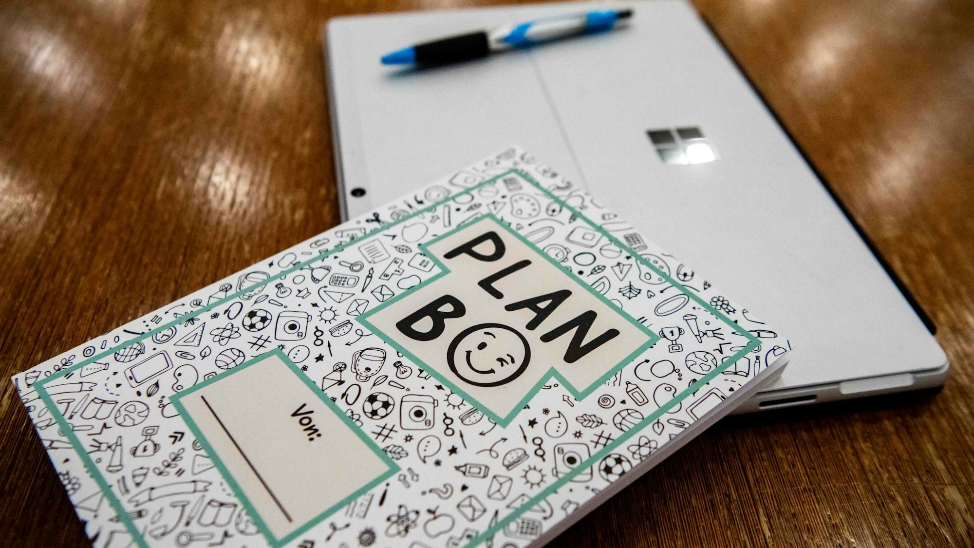 Das Bild zeigt das Notizbuch auf einem Tisch liegen. Auch ein Stift und ein Tablet sind zu sehen.