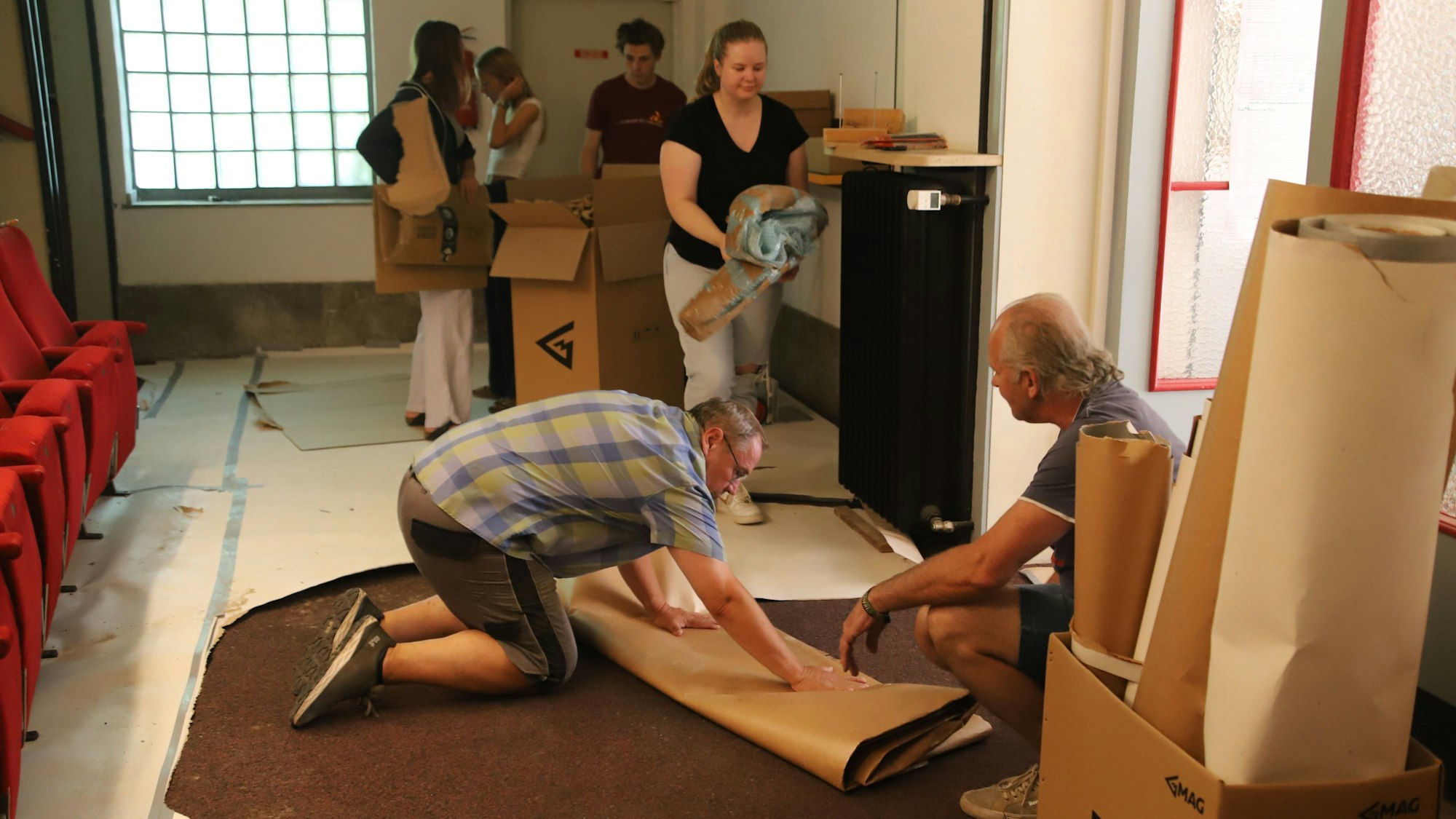 Ehrenamtliche Helfer entfernen die Schutzfolien von den Böden und entsorgen Verpackungen.
