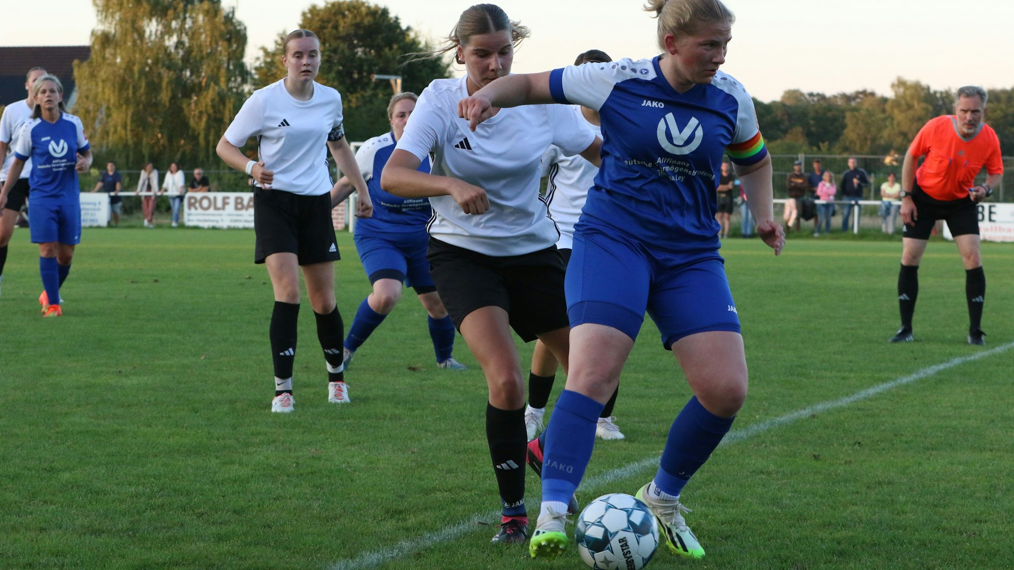 Erfthöhens Spielerin schirmt den Ball gegen eine Kommerner Gegenspielerin ab. Der Schiedsrichter schaut ganz genau hin, ob alles mit rechten Dingen zugeht.