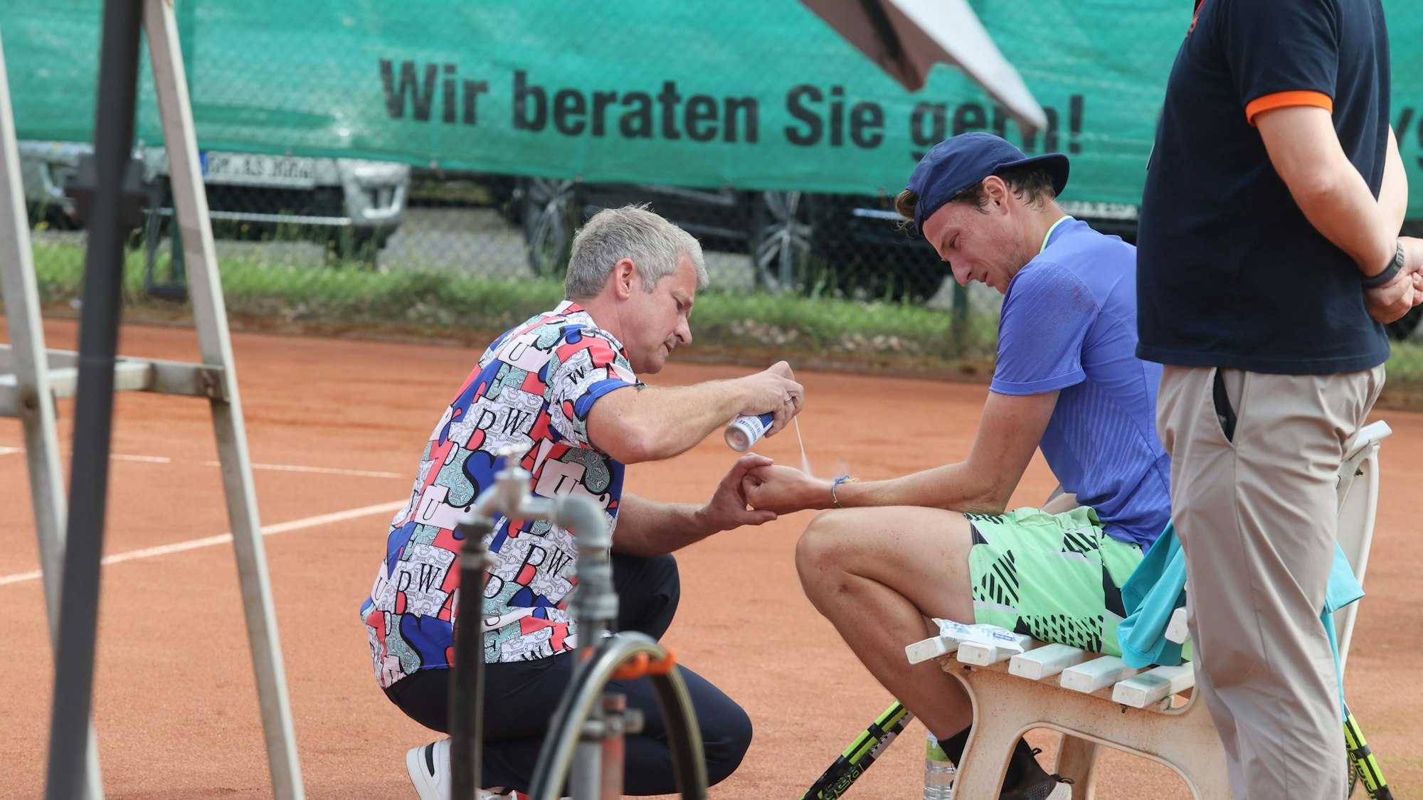 Tennisspieler Gabriel Décamps wird am Rande eines Turniers am Handgelenk behandelt.