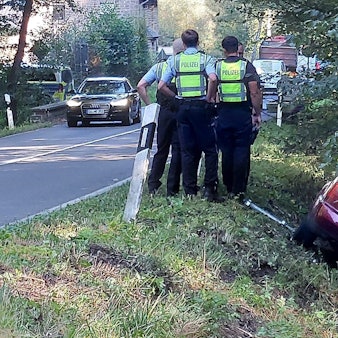 Der Wagen eines Verdächtigen liegt im Graben, Polizisten stehen daneben.