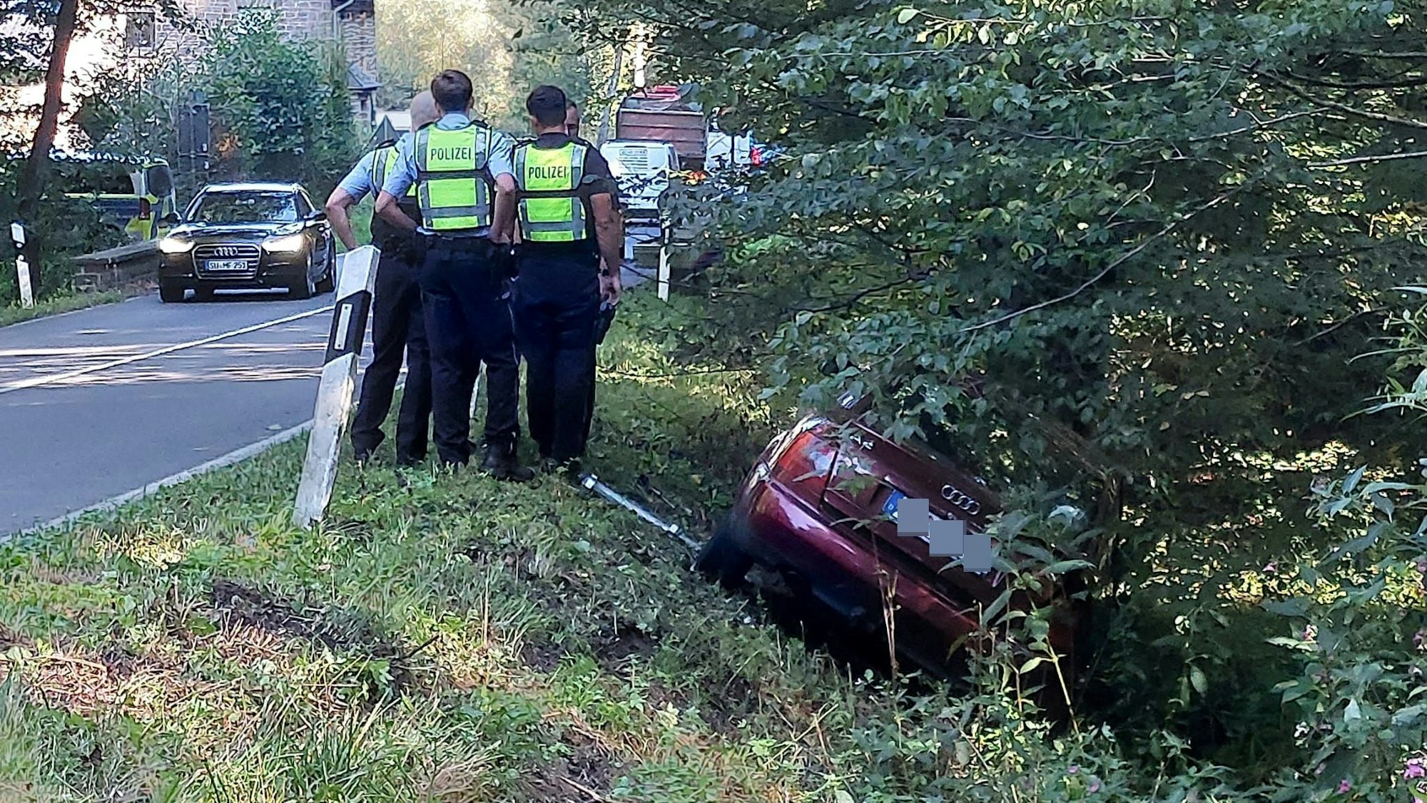 Der Wagen eines Verdächtigen liegt im Graben, Polizisten stehen daneben.