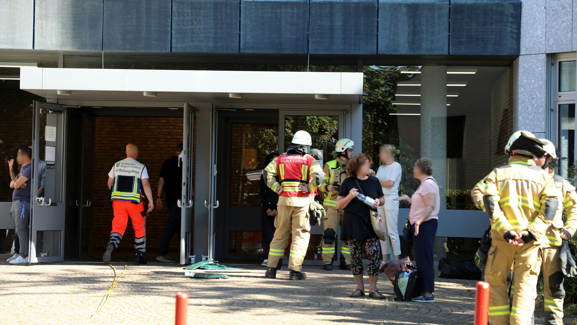 Feuerwehrleute und Lehrer stehen vor dem Berufskolleg Kaufmännische Schulen in Bergisch Gladbach-Heidkamp.