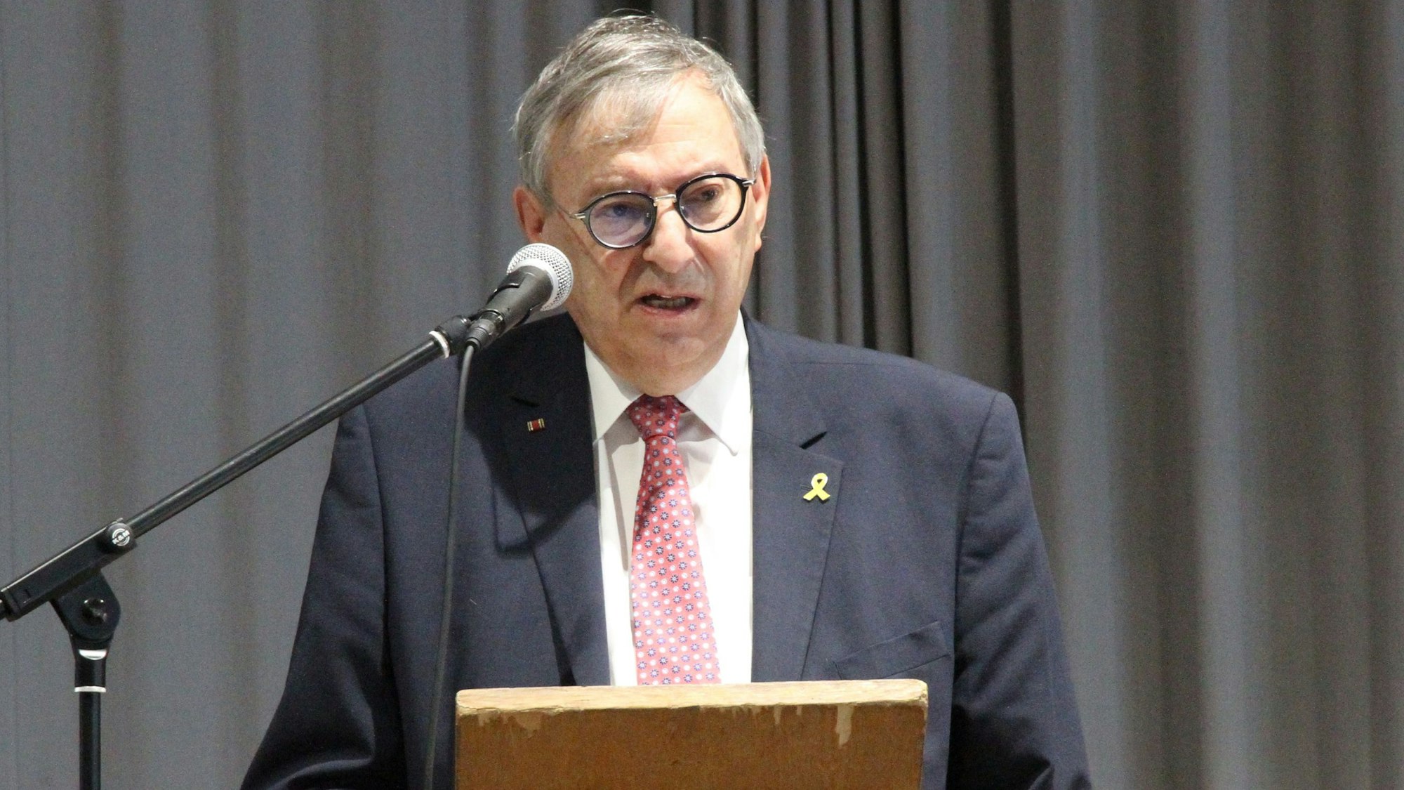 Ein Mann in einem grauen Anzug an einem Rednerpult